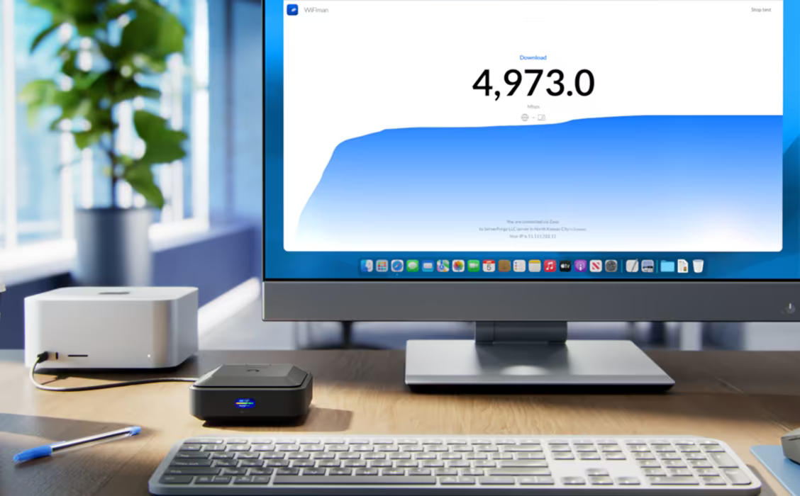 Ubiquiti U-AirWire UniFi AirWire on a desk beside a computer monitor displaying a WiFiman speed test