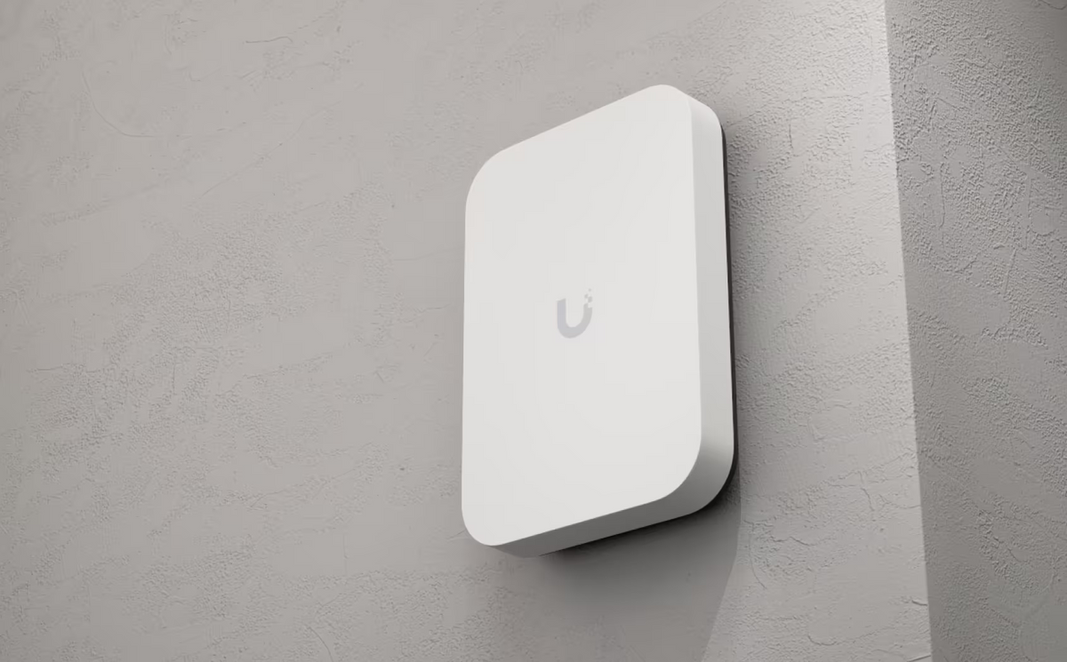 Ubiquiti U7-Pro-XG-Wall UniFi U7 Pro XG Wall mounted vertically on a textured wall, showing the rounded front panel and side profile