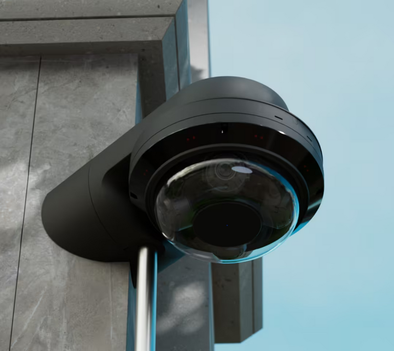 Ubiquiti UACC-AI-MS-4-AM-B UniFi AI Multi Sensor 4 black camera arm mount supporting a dome camera at a building corner with vertical conduit below.