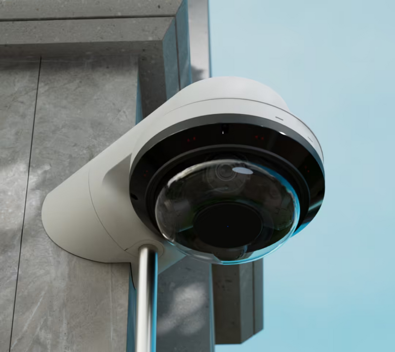 Ubiquiti UACC-AI-MS-4-AM-W UniFi AI Multi Sensor 4 white camera arm mount installed on a building corner with a camera and cable conduit.