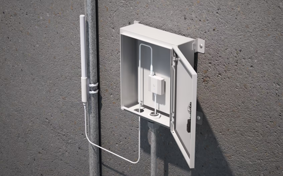 UniFi SuperLink high-gain antenna installed on a pole and cabled to Ubiquiti equipment inside an outdoor enclosure
