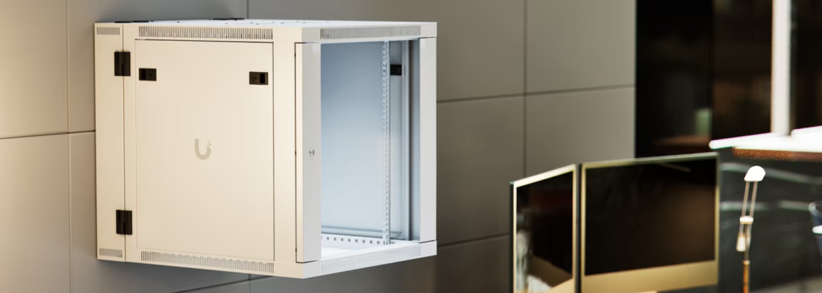 Ubiquiti UACC-Rack-12U-Wall-SW-G UniFi Swing 12U Rack Cabinet wall-mounted beside office workstations, with glass front door and lockable side panel.