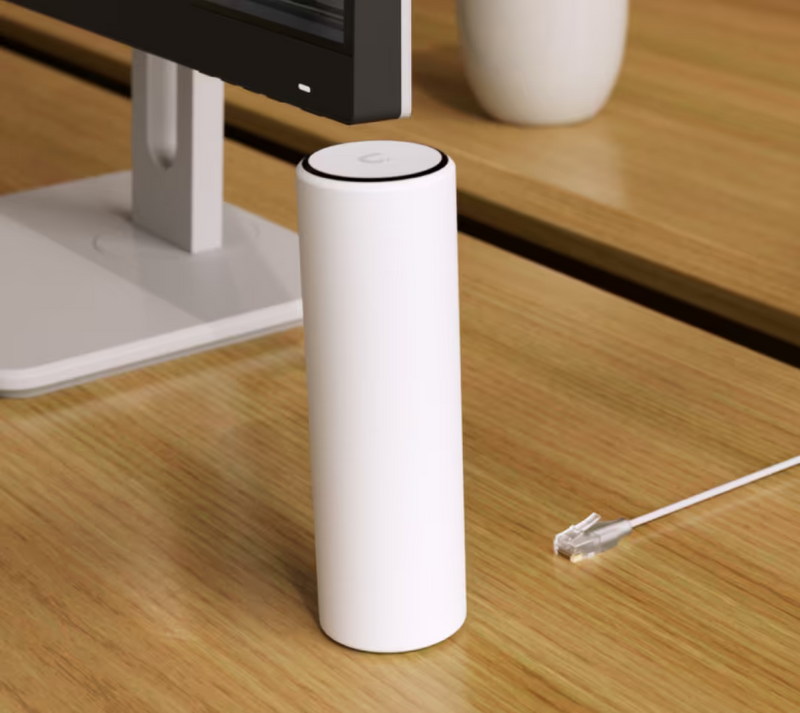 Ubiquiti U7-Mesh UniFi U7 Mesh WiFi access point beside a monitor with an unplugged Ethernet cable on the desk.