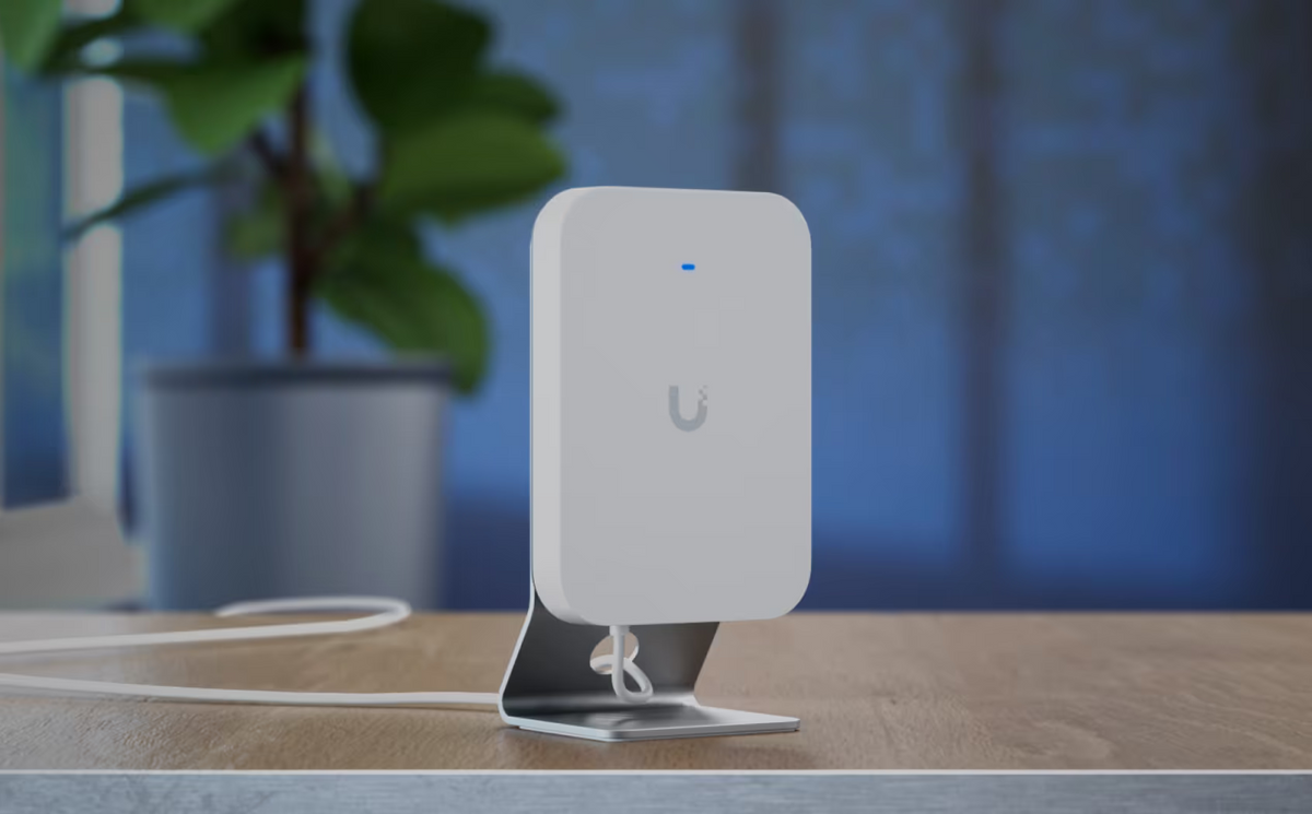UniFi U7 Pro XG Wall access point mounted on the Ubiquiti table stand with cable routed across a desktop