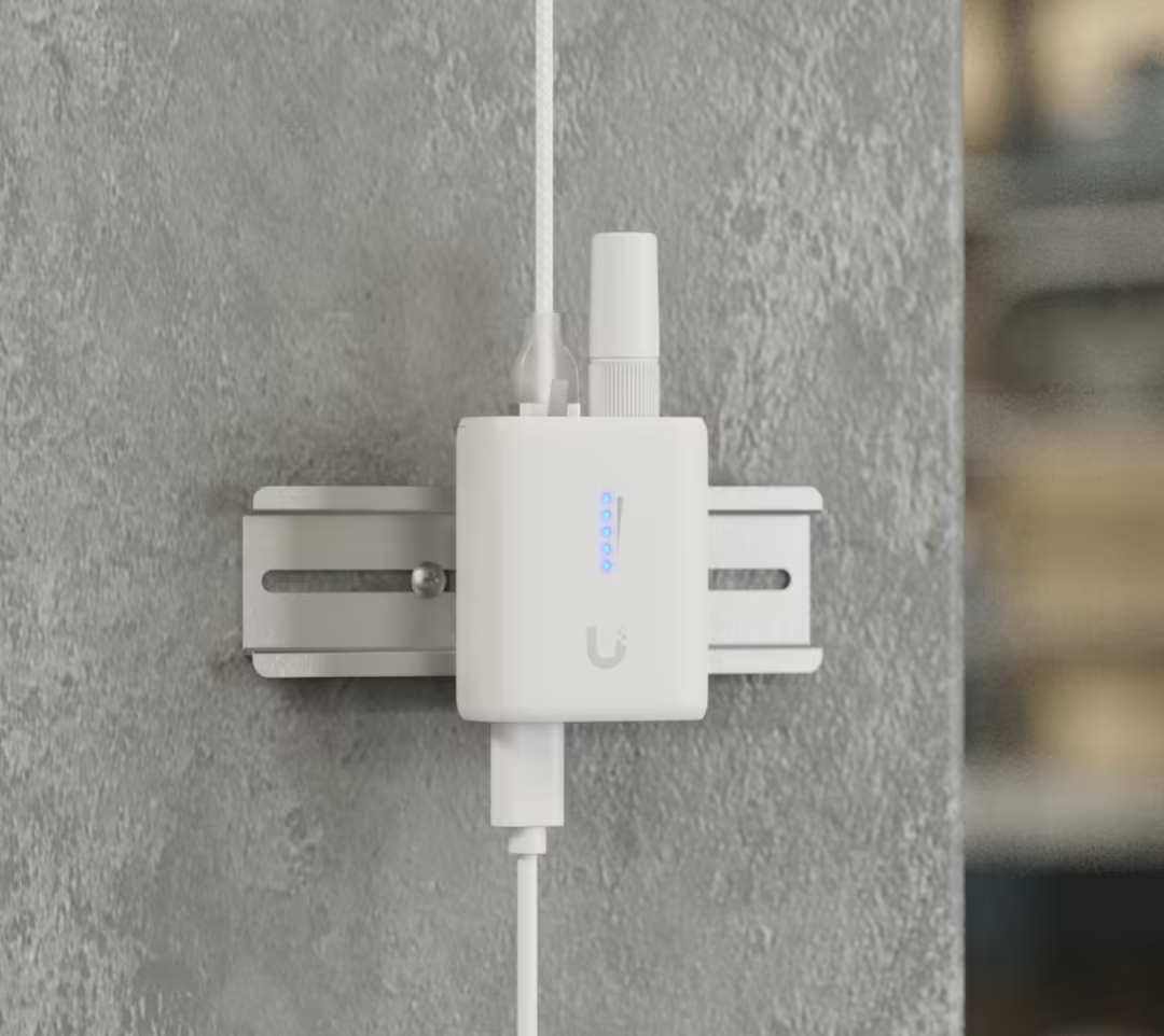 Ubiquiti UDB-IoT UniFi Device Bridge IoT mounted on a DIN rail with antenna, connected cables and blue status LEDs