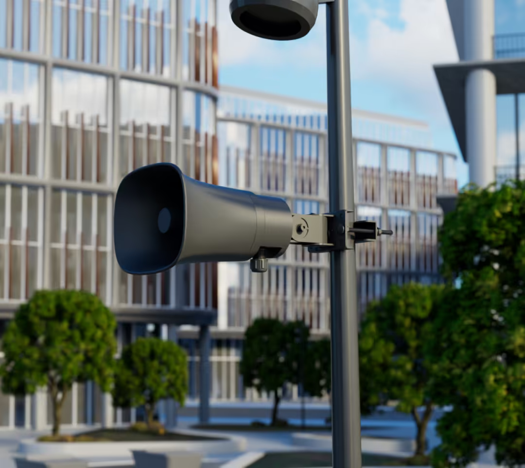 Black Ubiquiti UniFi UP-AI-Horn-Speaker installed on a street-light pole outside a modern commercial building