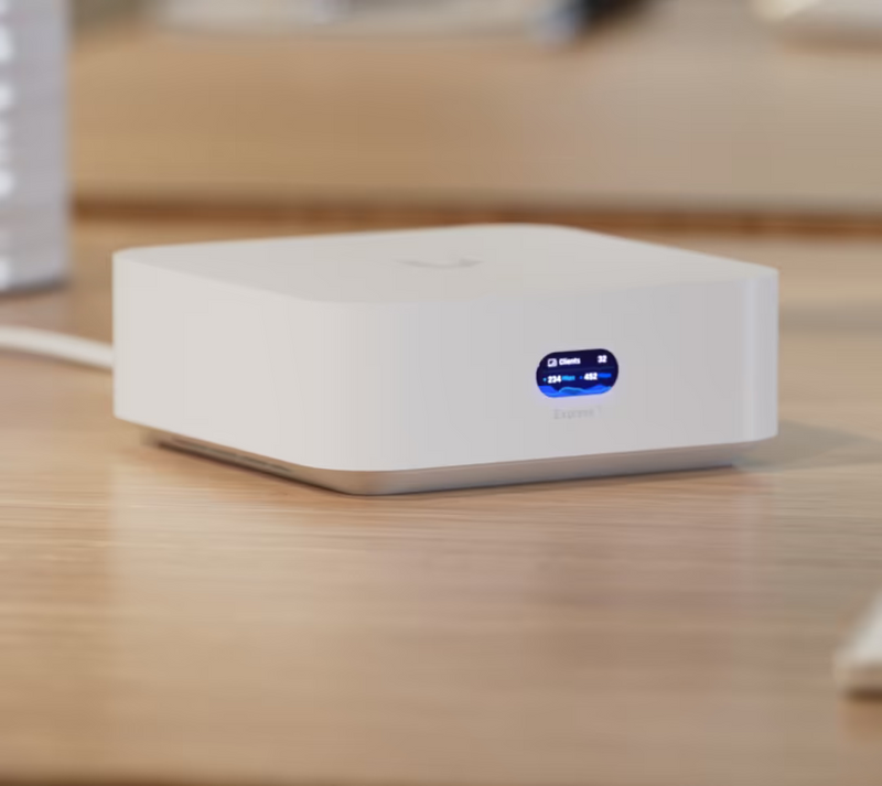 Ubiquiti UX7 UniFi Express 7 on a wooden desk, showing its white enclosure and illuminated front status display.